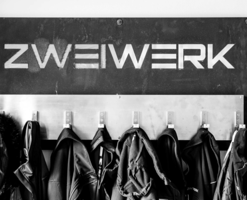 Jacken an einer Garderobe mit dem Zweiwerklogo darüber